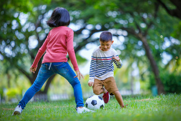asian boy and girl enjoying with soccer game at outdoor
