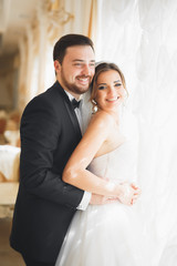 Fototapeta premium Gorgeous groom gently hugging stylish bride. Sensual moment of luxury wedding couple