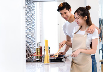 Young couple asian together man and woman cooking food for dinner salad with spaghetti menu in kitchen room and home romantic indoor sweet, happy