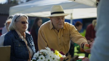  Senior couple shopping at a farmers market - Powered by Adobe