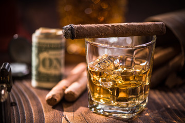 Glas with Whiskey over ice cubes and cuban cigar