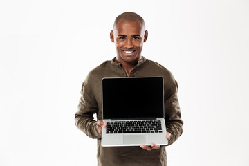 Happy african man showing blank laptop computer screen