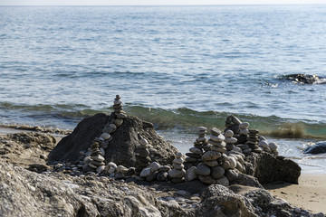 Scenic View Of Balanced Stones Stacked On Rocks Near Beach And Ionian Sea