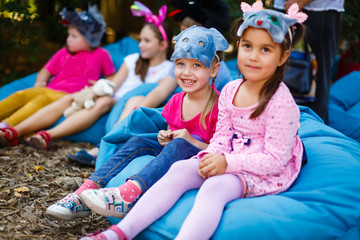 happy two little girls in masks on soft padded stools