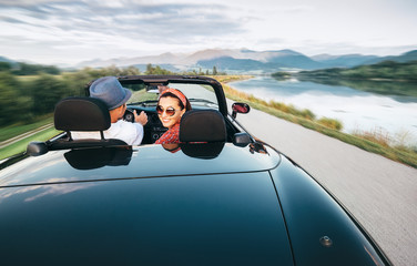 In love couple traveling by cabriolet car - obrazy, fototapety, plakaty
