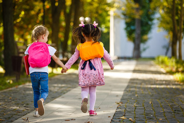 Two happy cheerful girls running to school