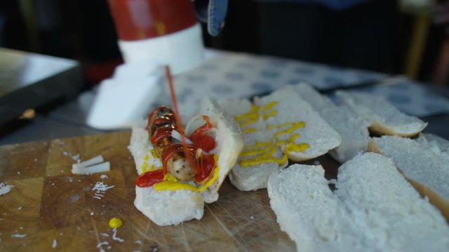  Street food vendor making hot dogs for customers at summer festival