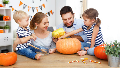 Fototapeta premium happy family mother father and children cut pumpkin for halloween