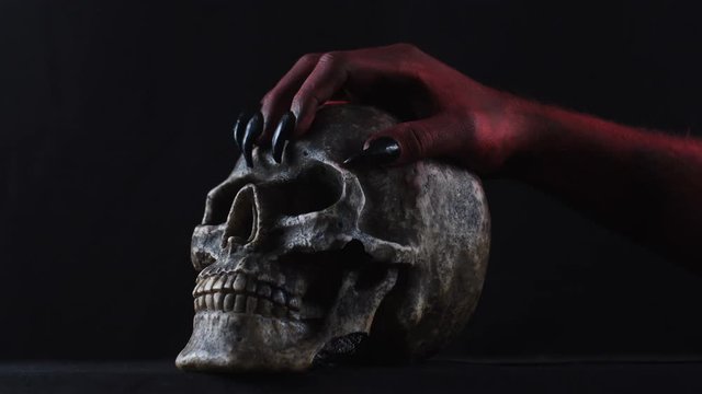 Red demon hand touching the skull.