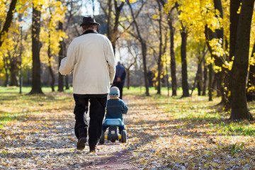 grandfather take care grandson in a park in autumn