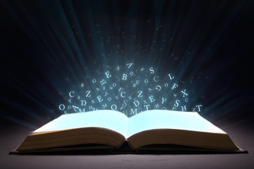 An open book with rays and glow and letters of the alphabet in levitation