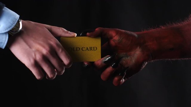 Red demon hand gives a gold credit card to the businessman.