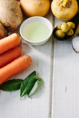 Vegetables, olives and spices over white wooden table.