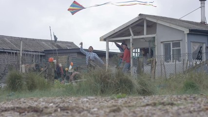 Happy friends at beach house, flying a kite & going for a run on the beach - Powered by Adobe