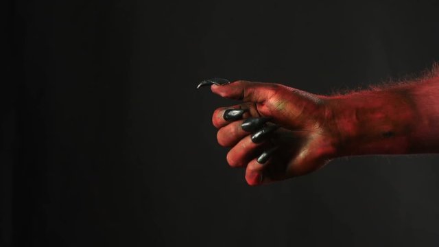 Red demon hand gives a cigarette to the man.