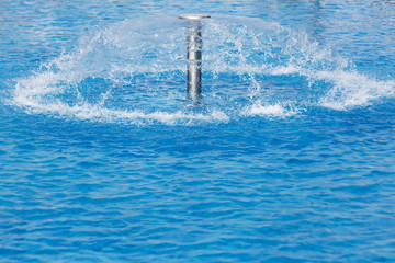 Mushroom spray fountain in an outside blue swimming pool
