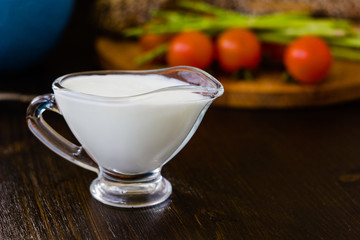 Natural cream dip in a glass bowl on dark wooden board.