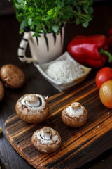 Mushrooms on board with fresh vegetables on background.