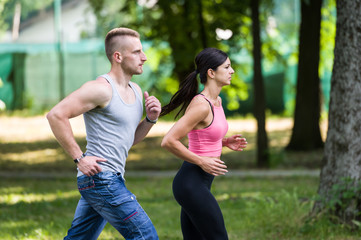 sport woman and man running together in a park in summer