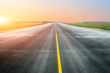 Asphalt road with a dividing strip in the horizon at sunset.