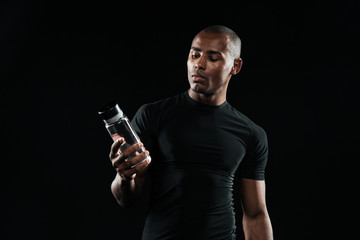 Young afro american sports man holding bottle of water