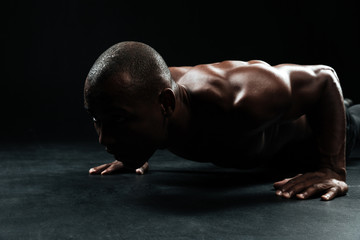 Close-up portrait of afro american sports man, with beautiful muscular body doing pushup exercise...