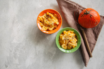 Pumpkin creamy mac and cheese baked pasta over white stone background. Comfort food.