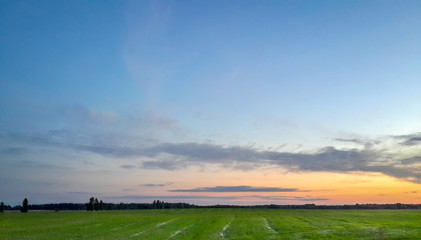 Spectacular landscape with green field and turquoise blue sunset sky