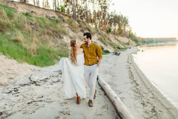 A young couple is having fun and walking on the sea coastline. Newlyweds looking at each other with tenderness. Romantic date on the beach. Wedding. Artwork