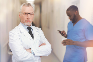 Obraz premium Serious grey-haired man keeping arms crossed on chest