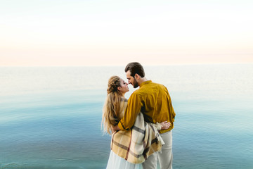 A beautiful couple is embracing on the sea background. Moment before the kiss. Romantic date on the beach. View from the back. Wedding. Artwork