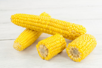 Boiled yellow ripe whole corn and slices of corn on old rural white wooden planks