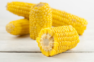 Boiled yellow ripe whole corn and slices of corn on old rural white wooden planks