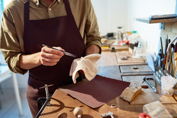Mid section portrait of unrecognizable jeweler finishing silver ring with precious stone in workshop