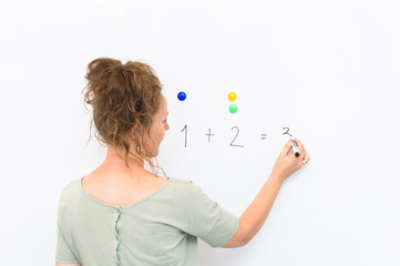 teacher woman teaches how to count on whiteboard in the classroom