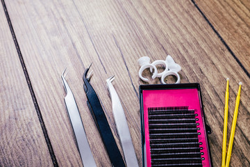 Eyelash Extension tools on wooden background. Accessories for eyelash extensions. Artificial lashes. Top view.