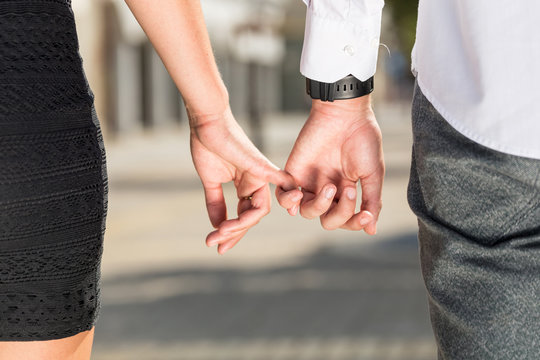 close up photo of young couple holding hands on street in summer