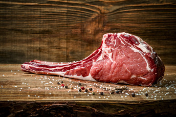 Dry aged raw tomahawk beef steak with ingredients for grilling