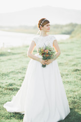 Fototapeta na wymiar Bride in wedding dress posing on grass with beautiful landscape background
