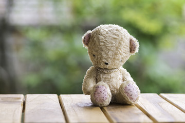 teddy bear sitting on wooden floor., background blurred..