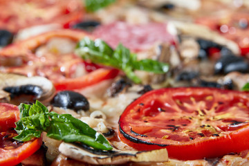 Closeup of pizza with salami, tomatoes and olives