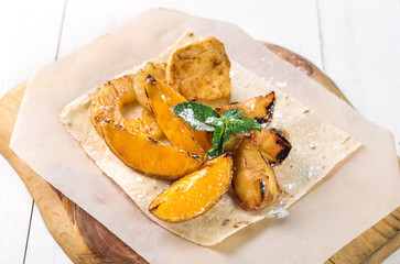 Fruits grilled with mint close up on a wooden board on the table.