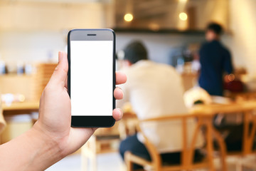 Man hand hold black smartphone isolated white screen for advertising display with people sitting in coffee cafe background