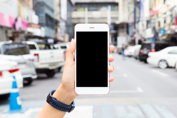 Hand holding mobile smartphone isolated black screen on cars parked on road background