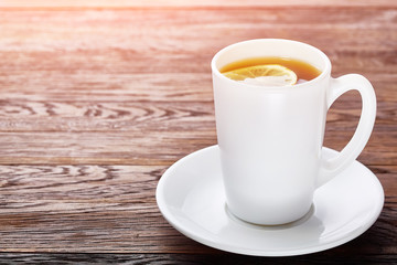 White porcelain cup of tea with cinnamon sticks, lemon, mint leaves and tea strainer