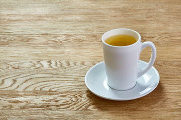 Cup of mint tea and green leaves on light table