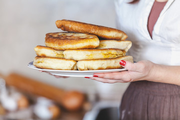 Women's hands holding plate of cakes with side view