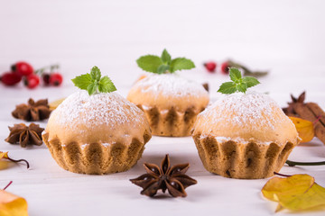 Autumn pastries. Homemade cupcakes with powdered sugar with cinnamon sticks, anise stars and autumn leaves