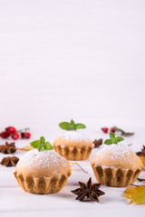 Autumn pastries. Homemade cupcakes with powdered sugar with cinnamon sticks, anise stars and autumn leaves