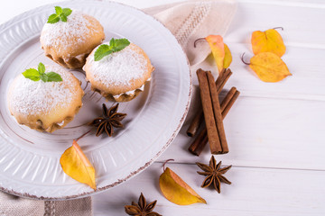 Obraz na płótnie Canvas Autumn pastries. Homemade cupcakes with powdered sugar with cinnamon sticks, anise stars and autumn leaves